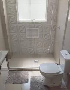 a white bathroom with a toilet and a window at Apartamento no centro de Caxias com elevador e garagem in Caxias do Sul