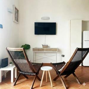 a living room with two chairs and a tv at Casa Nina-Bacoli Elegant & View in Bacoli