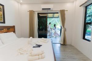 a bedroom with a white bed with two people walking outside at La Patria Chica in Sampong +7 photos