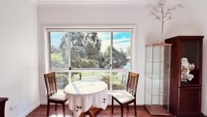 a dining room with a table and chairs and a window at Golf Course Frontage House in Schofields
