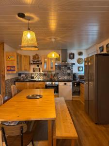 a kitchen with a wooden table and a refrigerator at Villa 1950 piscine et spa- Gérardmer - terrain entièrement clos pour animaux in Anould +20 photos