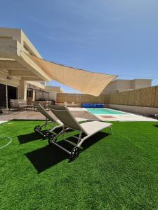 a lawn chair sitting on the grass in front of a house at וילת האושר אילת in Eilat
