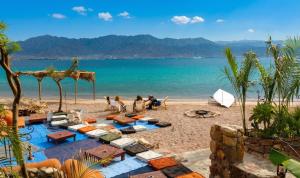 a beach with people sitting on the sand and the water at וילת האושר אילת in Eilat