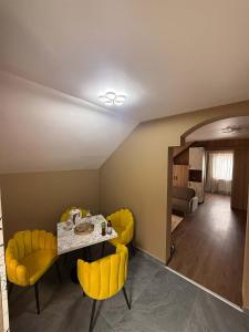 a dining room with a table and yellow chairs at Eclipse grill and pizza in Corunca