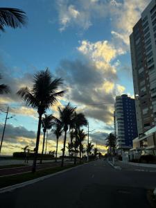 an empty street with palm trees and a cloudy sky at Casa 100mtrs do mar com piscina aquecida in Solemar