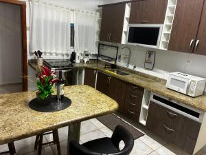 a kitchen with a counter and a table with a microwave at Casa 100mtrs do mar com piscina aquecida in Solemar