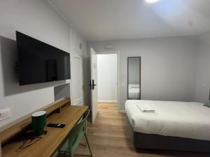 a bedroom with a bed and a desk with a television at Hostal Guzman El Bueno by gaiarooms in León +19 photos