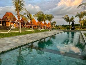 a swimming pool in front of a resort with palm trees at Casa Tibubiu in Tabanan