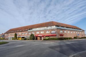 a large brick building with a red roof on a street at Hotel Schöne Altmark in Kalbe