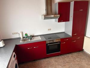 a red kitchen with a sink and a stove at Gästeapartment in ruhiger Lage in Rainau