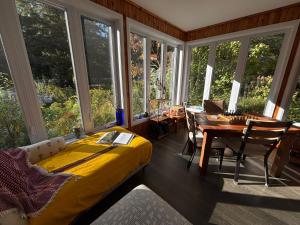 a room with a bed and a table and windows at Gîte du Lac-à-la-Loutre - B&B in Huberdeau