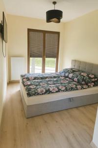 a bedroom with a bed with a floral comforter at Bursztynowy Horyzont Śliwin obok Rewal , Pobierowo in Śliwin