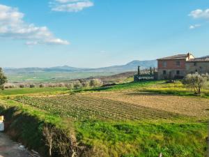 a view of a farm field with a house in the background at My Tuscany Green Apartment in San Quirico dʼOrcia