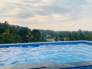 a swimming pool in a resort with trees in the background at AJ Wayanad Suites in Kalpetta