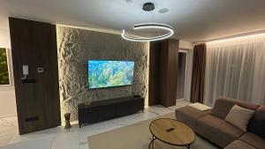 a living room with a couch and a tv on a wall at Apartmán beige Bardejovské Kúpele in Bardejov