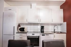 a white kitchen with white cabinets and a microwave at Hovfjällstoppens Stugby in Överbyn