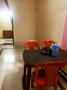 a black table with orange chairs and a cup on it at skyparking Golden cottage in Salem
