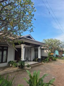 a white house with a tree in front of it at d'Alvin Homestay 2 in Labuan Bajo