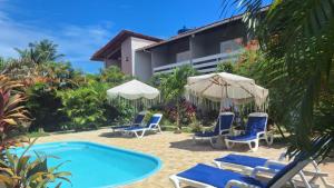 a resort with a swimming pool with chairs and umbrellas at Pousada Maresia in São Miguel dos Milagres