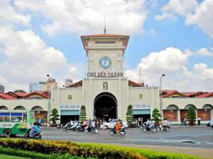 a clock tower in front of a building with people on motorcycles at Journey Central - Ho Chi Minh City - SOHO RESIDENCE in Ho Chi Minh City