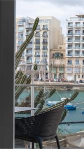 a window with a chair and a view of a harbor at Seafront, lovely modern studio. in St. Julianʼs