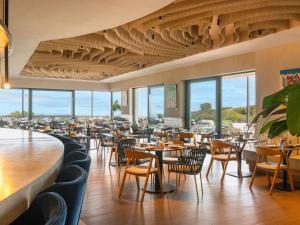 a dining room with tables and chairs and windows at SO Sotogrande Spa and Golf Resort Hotel Costa del Sol in Sotogrande