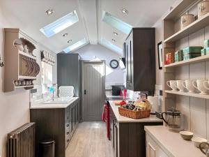 a kitchen with gray cabinets and a ceiling with skylights at Jasmine Cottage in Grassington