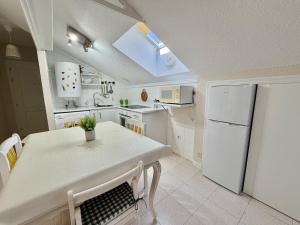 a white kitchen with a table and a refrigerator at Apartamento Somo 30608 in Somo +4 photos