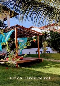 a wooden bench sitting in the grass next to a house at Pousada Caliandra Pipa in Pipa