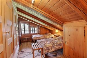 a bedroom with two beds and a bench in a room at Chalet Vallonette in Chateau-d'Oex