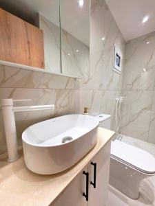 a white bathroom with a sink and a toilet at Anthouli Homes 2, steps from beach and centre in Kardamaina