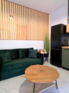 a living room with a green couch and a table at Anthouli Homes 2, steps from beach and centre in Kardamaina