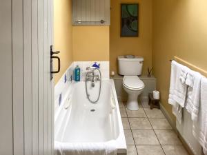 a bathroom with a tub and a toilet at Stepping Gate Cottage in Scalby