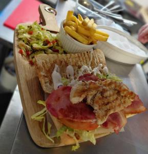 a sandwich on a cutting board with french fries at Fleur De Lis Hotel in Sandwich +15 photos
