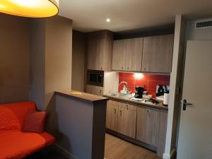 a small kitchen with wooden cabinets and a red couch at Studio au-dessus de l'Orne in Caen