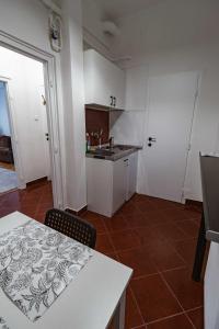 a kitchen with white cabinets and a table and a counter at LénApartman - Holiday in Pécs +4 photos