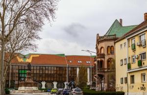 a building with a statue in the middle of a street at LénApartman - Holiday in Pécs