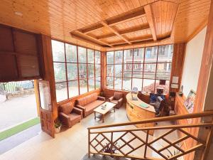 a living room filled with furniture and windows at New Suraj Inn - Nestled near Hadimba Temple ! Rooftop Cafe ! Private Parking in Manāli