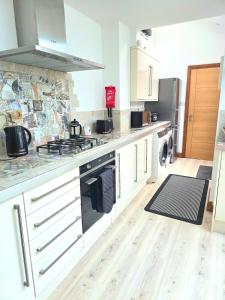 a kitchen with white cabinets and a stove top oven at Orebank Cottage in Millom +5 photos
