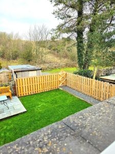 a backyard with a wooden fence and green grass at Orebank Cottage in Millom