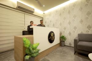a man and woman standing at a reception desk at Avsar Resort in Verāval