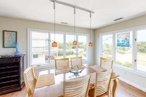 ein Esszimmer mit Tisch, Stühlen und Fenstern in der Unterkunft Palms Delight in Kitty Hawk