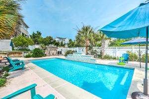 ein Schwimmbecken mit blauen Liegestühlen und einem Sonnenschirm in der Unterkunft Palms Delight in Kitty Hawk
