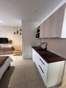a kitchen with a sink and a living room at Studio Tulum - jacuzzi privé - face à la mer in Tartane