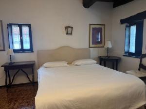 a bedroom with a bed with two tables and two windows at Locanda Motto del Gallo in Taverne +3 photos