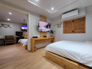 a bedroom with two beds and a tv and a desk at Orago Stay Hotel in Suwon