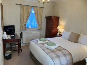 a bedroom with a bed with a desk and a television at Chapel House in Atherstone