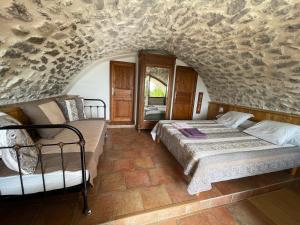 a bedroom with two beds and a stone wall at Les Dolines in Balazuc