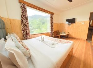 a bedroom with a large bed with a large window at New Suraj Inn - Nestled near Hadimba Temple ! Rooftop Cafe ! Private Parking in Manāli
