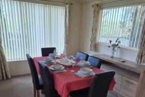 a dining room with a table with a red table cloth at 2 Bed Caravan - Sleeps 6 - Pets - Pool - Parking in Newquay +8 photos